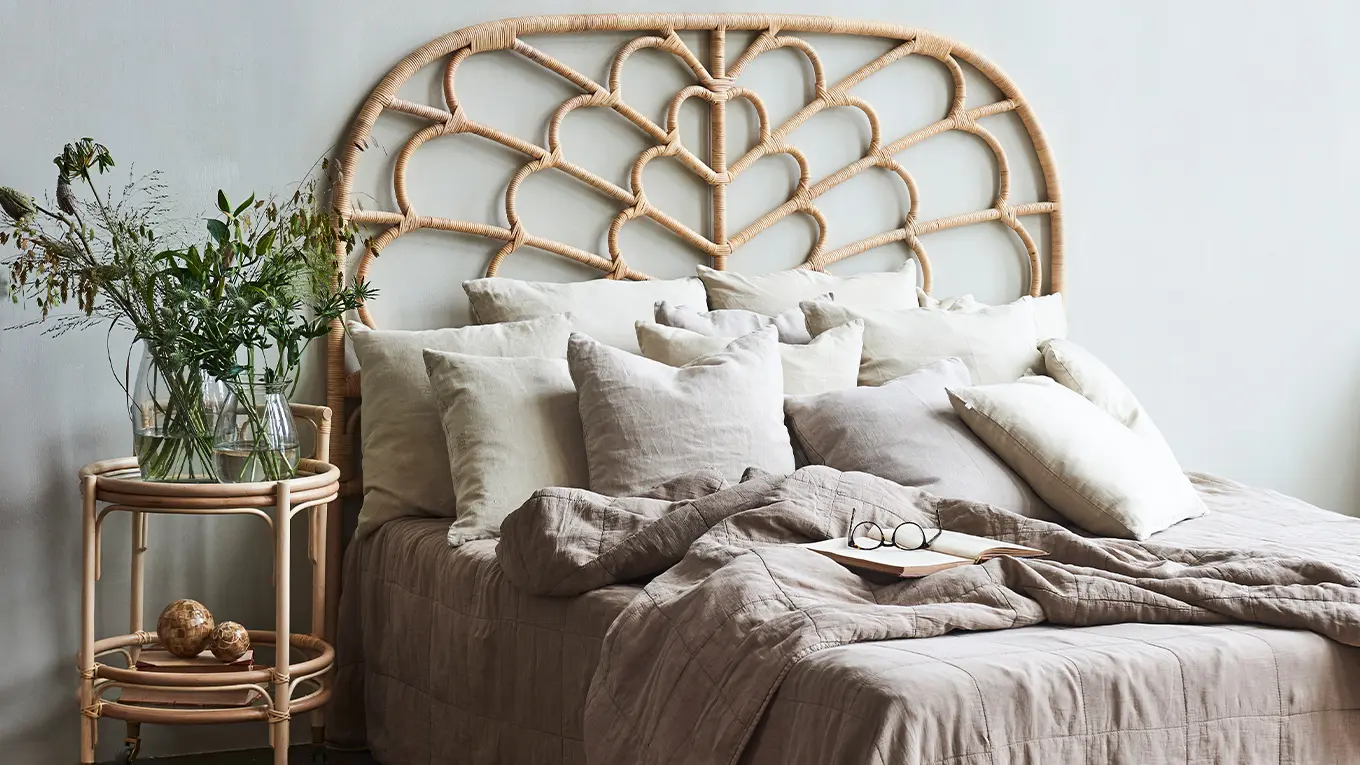 Sika Design Schlafzimmer mit Rattanbett, rattan nachttisch, tagesdecke und vielen kissen aus leinen