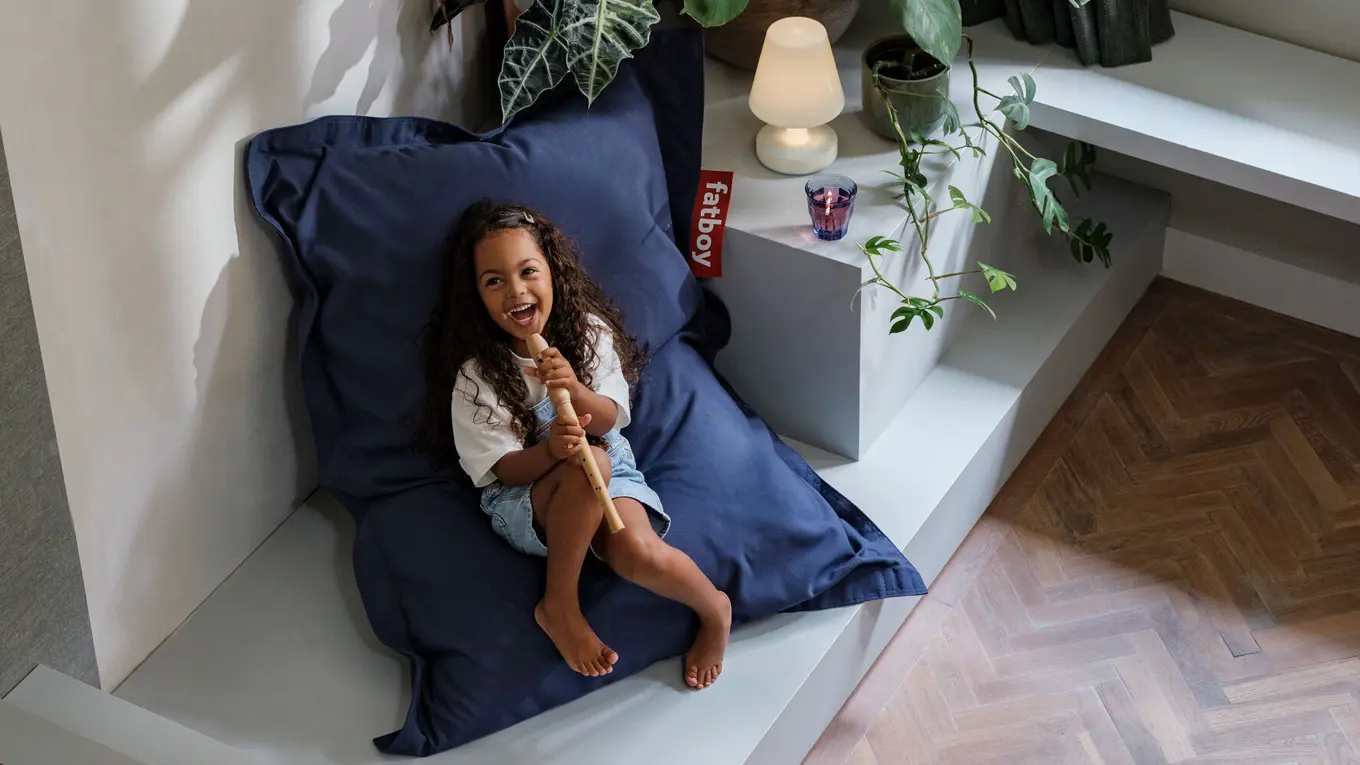 Mädchen mit flöte sitzt auf einem fatboy junior kinder sitzsack